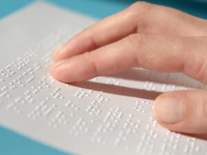 Image of a hand reading a page of braille.